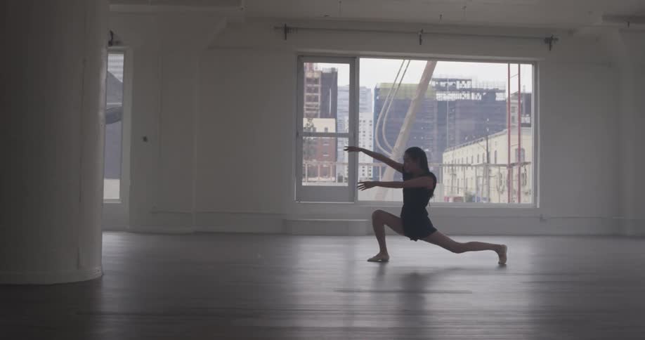 A woman in a dance studio does some unique dancing movements