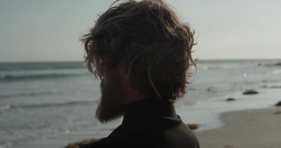A man standing on the beach is looking at the water