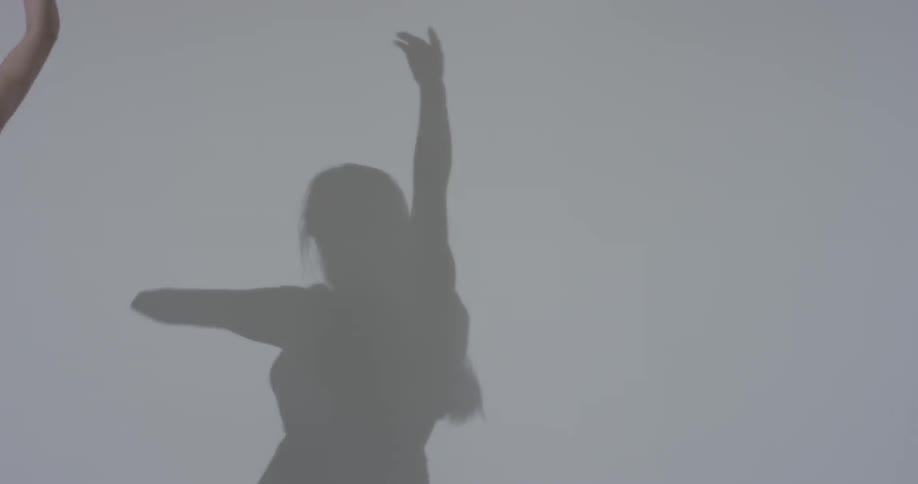 A woman that is dancing in front of a white wall