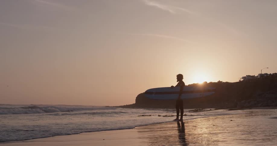 A man standing at the edge of the coast with a surfboard