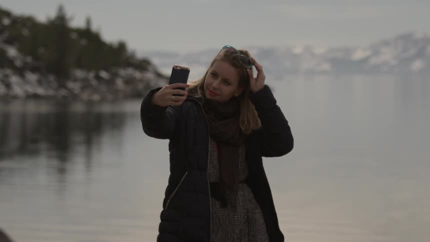 A woman using her phone as a mirror to check her hair