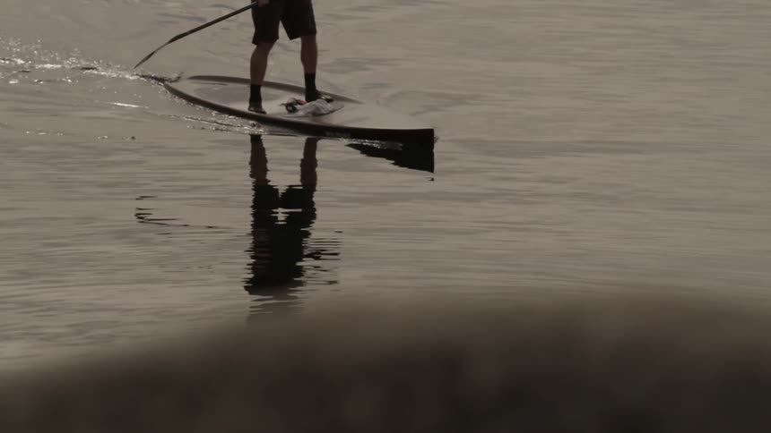 A person standing and paddling a boat