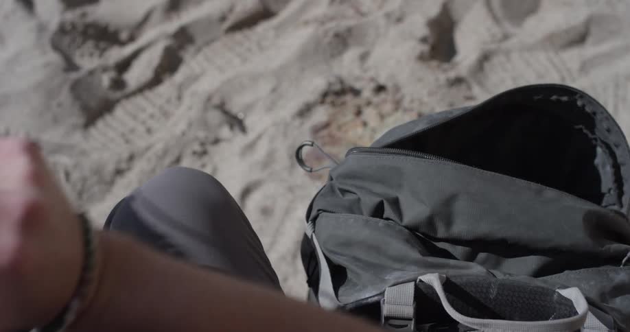 Man takes shoes out of backpack on trail