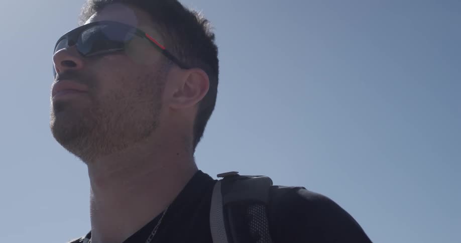 Man with sunglasses and backpack staring into the distance