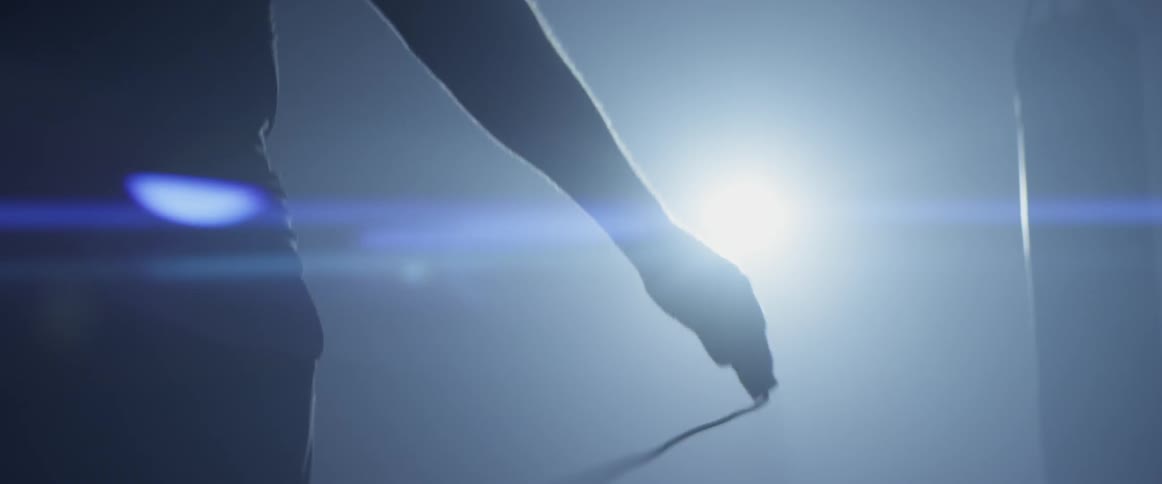 Man jumps rope indoors in dim light