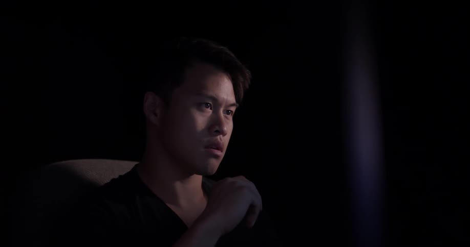 A man has his hand near his face thinking about what is on the screen