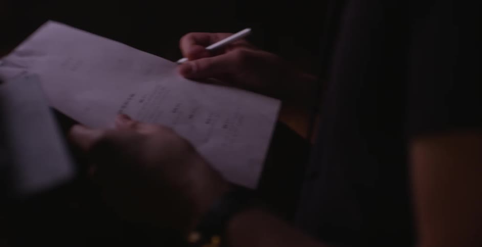 A woman hands a piece of paper to a man