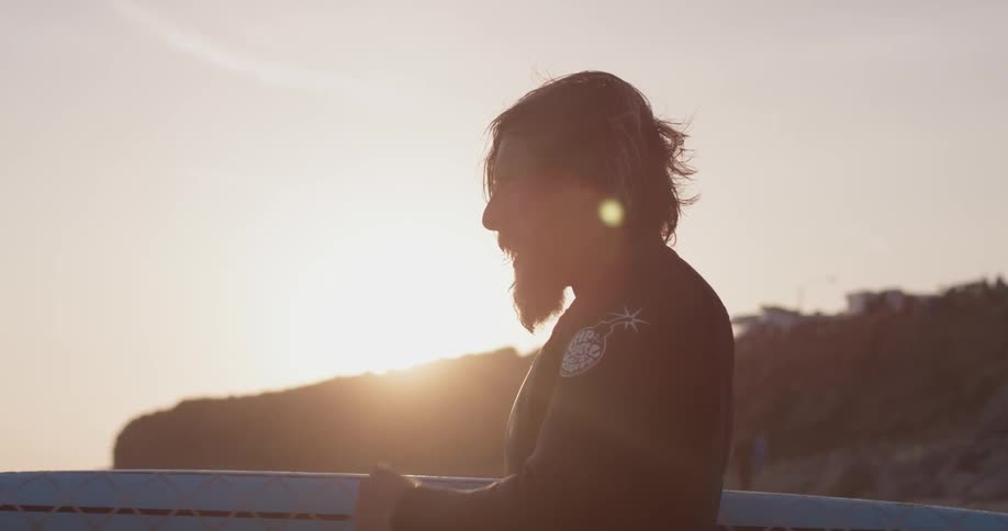Man in a wetsuit standing near the ocean holding a surfboard