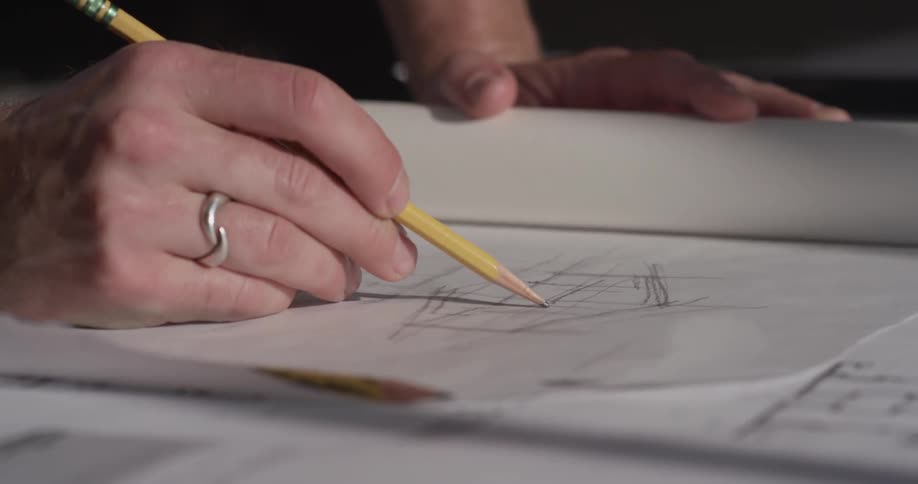 A hand is sketching a design on paper