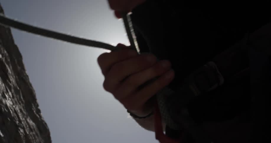 A man that is tying a knot on a rope for rock climbing
