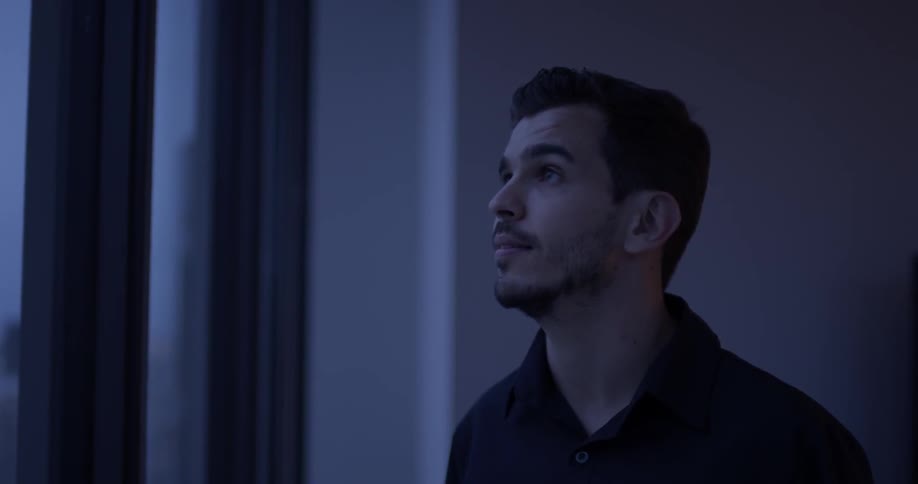 Man looks through windows outdoors in dim light