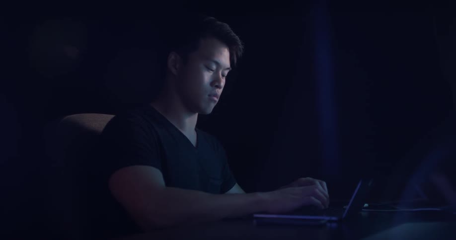 A man sitting at a desk typing on a laptop
