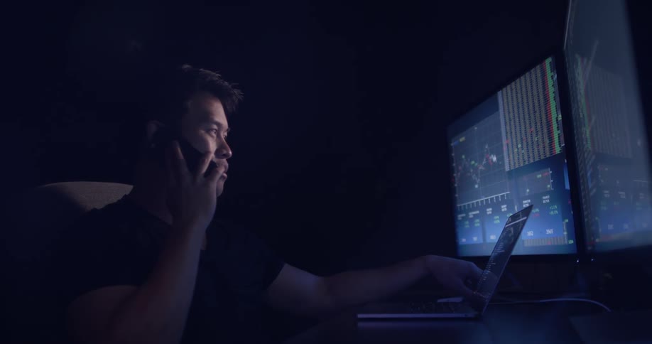 A man talking on his phone while working in a dark office