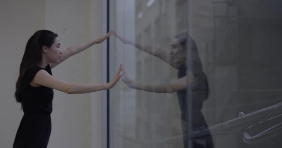 Woman dances in front of a large window in a studio in the city