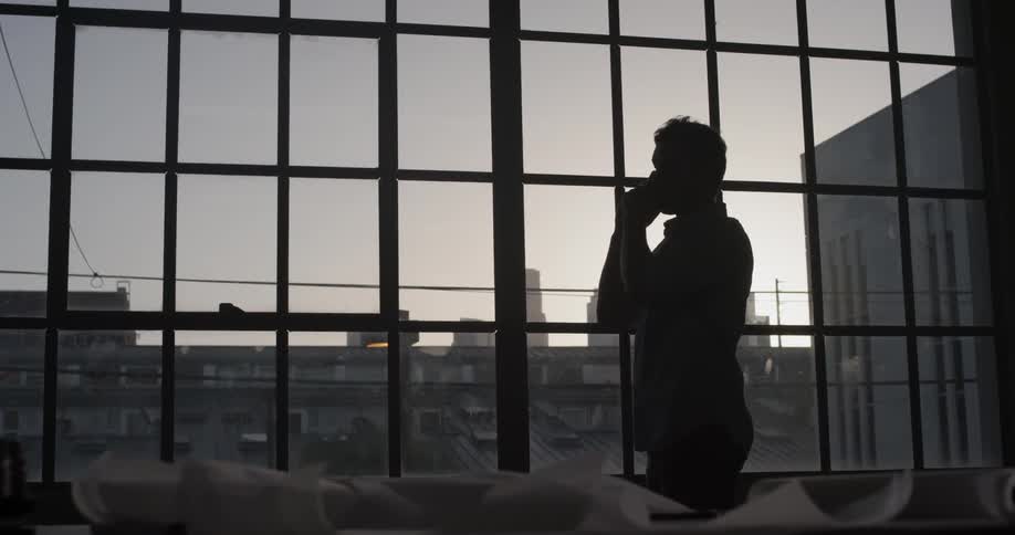 A man talking on a cell phone in front of a window