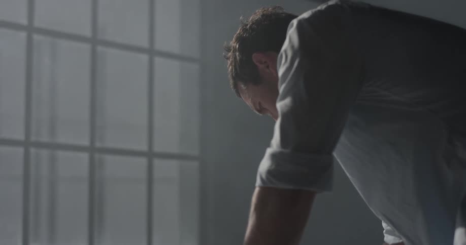 A man in a dark room leans over looking at something