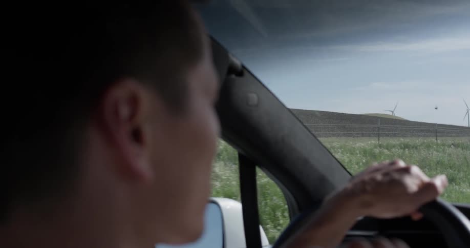 A man driving a car next to a grassy field