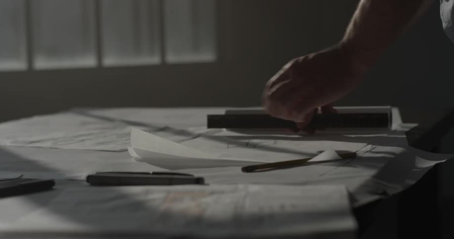 A man tearing pieces art drawn on paper off a large roll