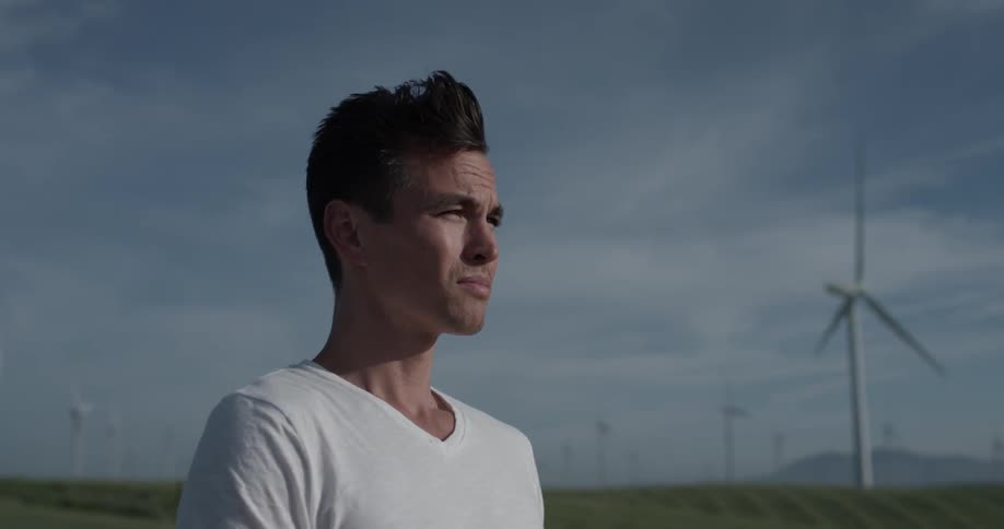 Man standing in a field of windmills