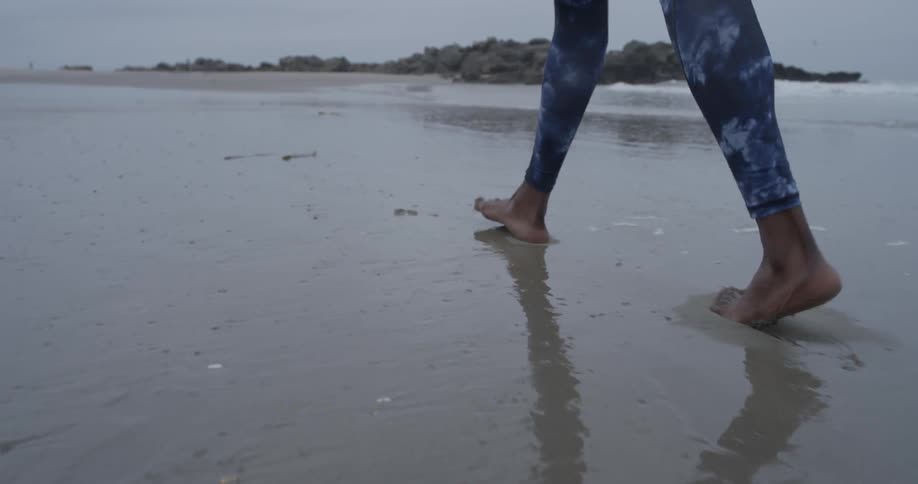 A person is walking down the beach making footprints