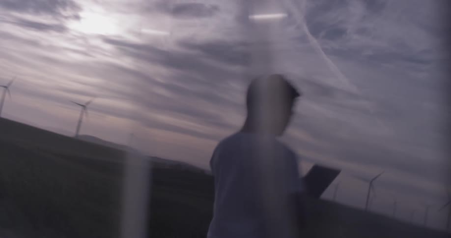 Man Driving Electric Car Through Wind Farm