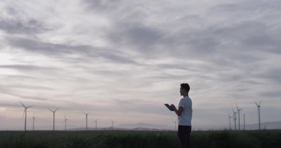 A man standing in a field working on a tablet