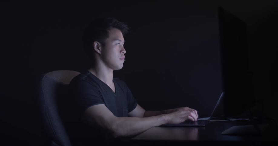 A man sitting at a desk typing on a laptop