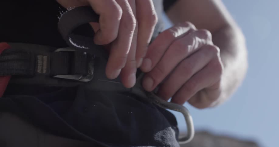 A person tightens their climbing gear