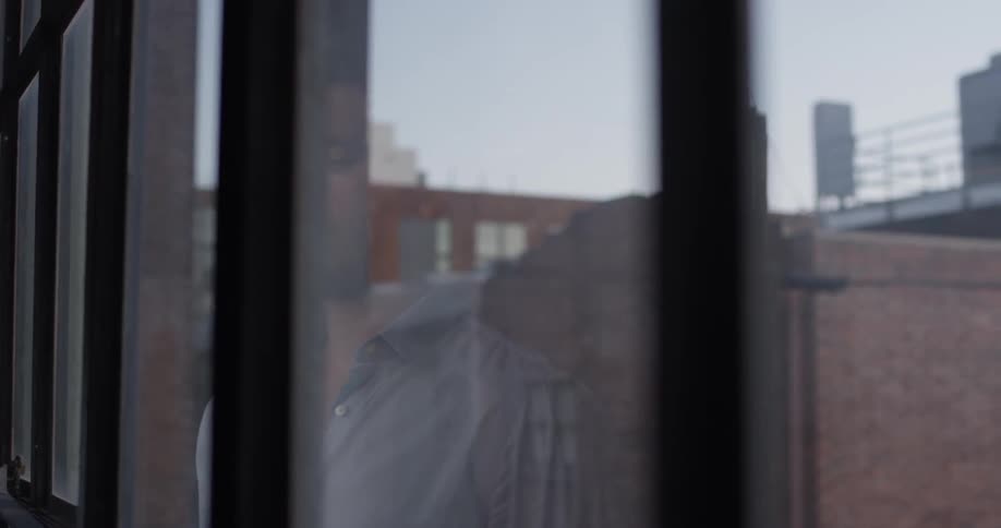 A man is staring out a large window