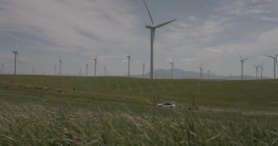 Man Driving Electric Car Through Wind Farm