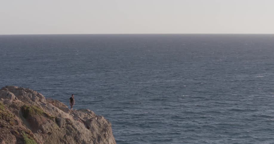 Man standing on top of a cliff high above the ocean