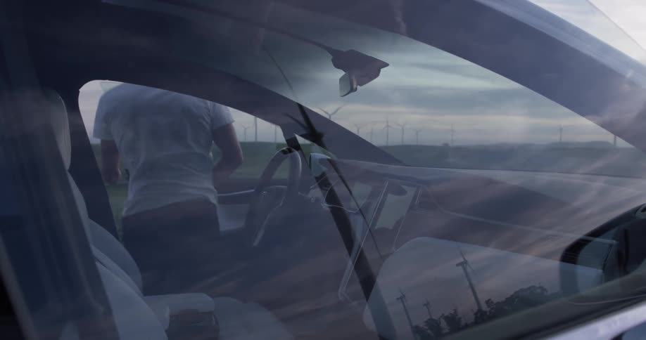Man getting out of a car near a wind farm