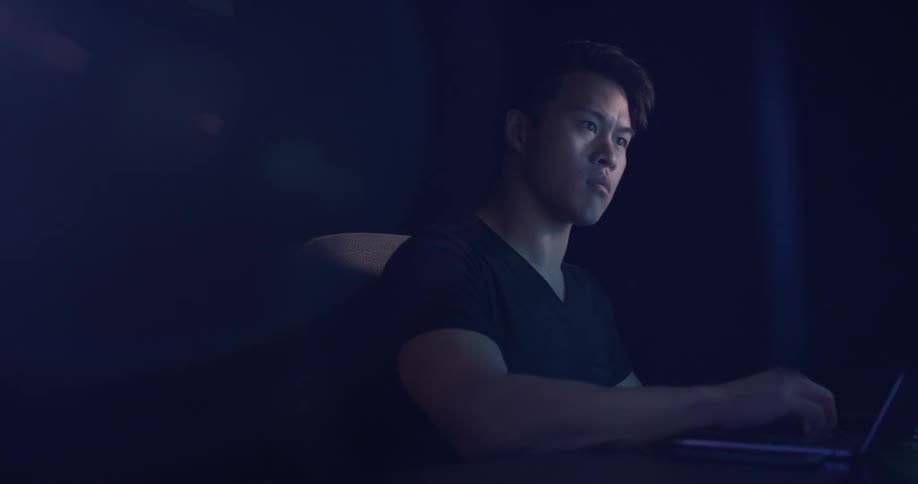 Man sits at desk and types on laptop while looking at another screen