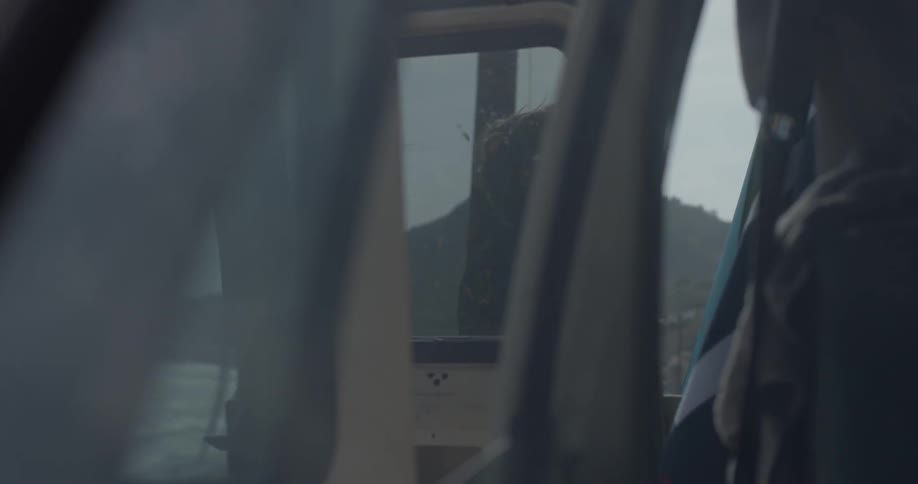 Man wearing a wet suit picking up his surfboard from against his van