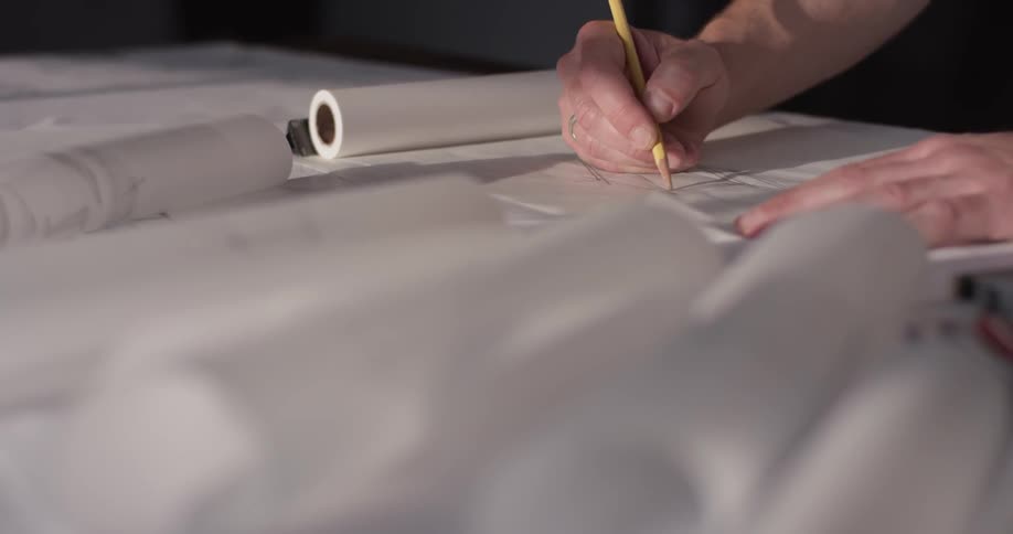 Someone makes a technical drawing on a paper on the table