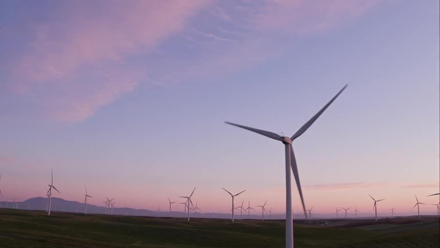 Man Driving Electric Car Through Wind Farm