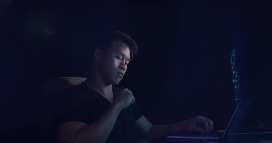 A man is looking at laptop indoors while he answers his phone
