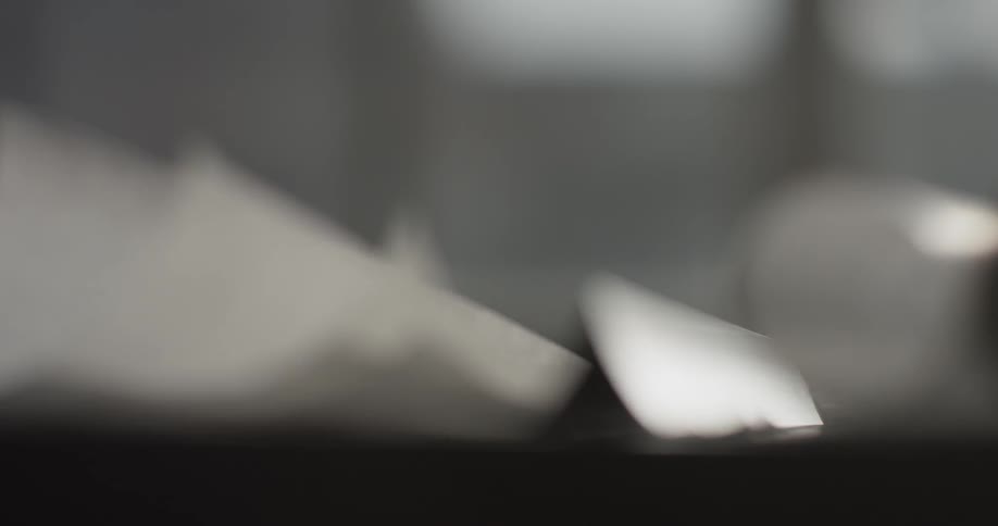 A human hand moves a ruler and some paper then writes on some paper