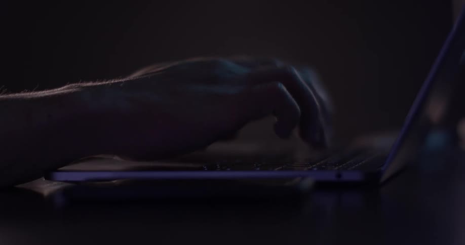 A man's hands are typing on a laptop keyboard