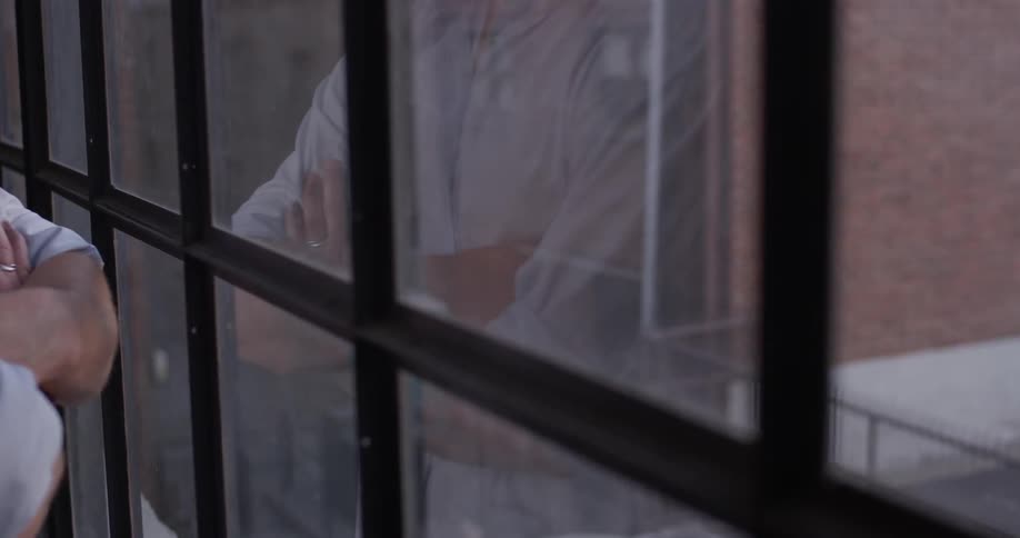 A man stands crossed armed at the window