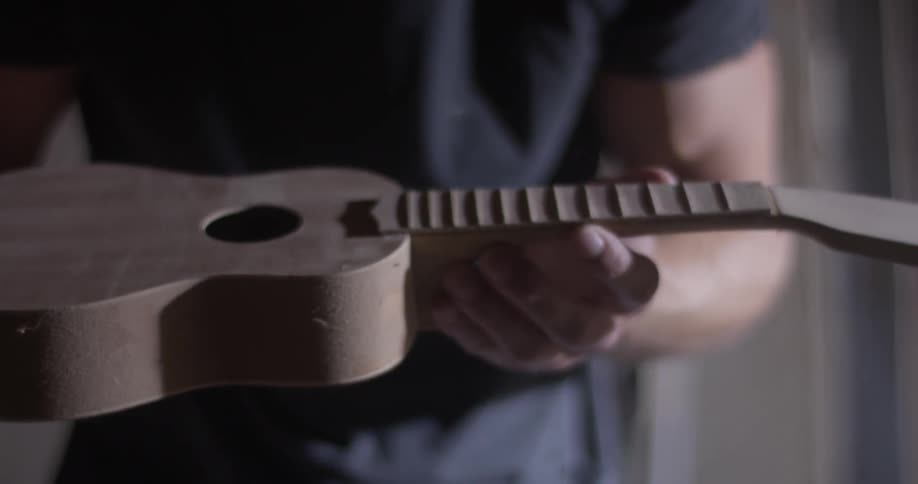 A man blows dust off of a wood instrument