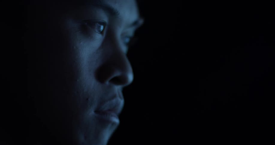 A man looking at a blue lit screen