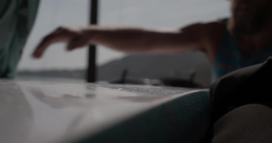 A man is opening a door and grabbing a surfboard