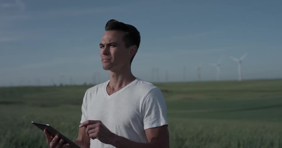 A man touches his tablet while looking to the distance