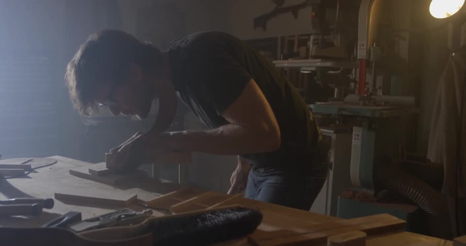 A man sawing some wood on a workbench