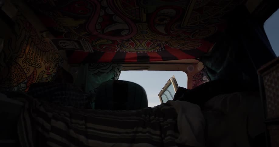 A man is pulling a surfboard out of the back of a vehicle