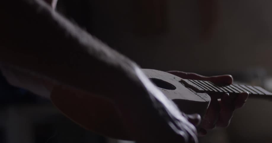 A man is brushing off a guitar indoors