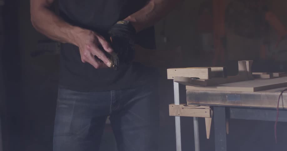 A man is using a tool to sand an object in his hand
