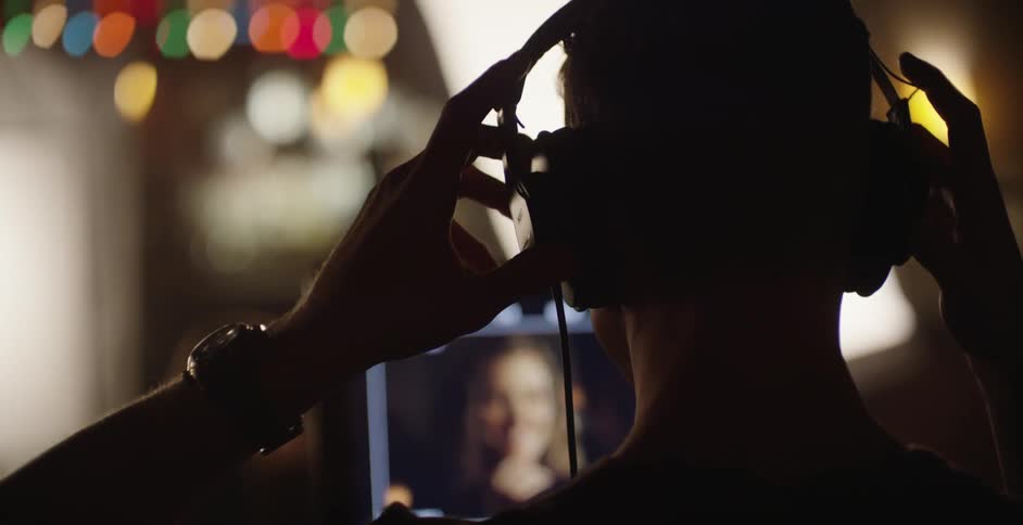 A man putting on headphones while sitting in front of a computer screen