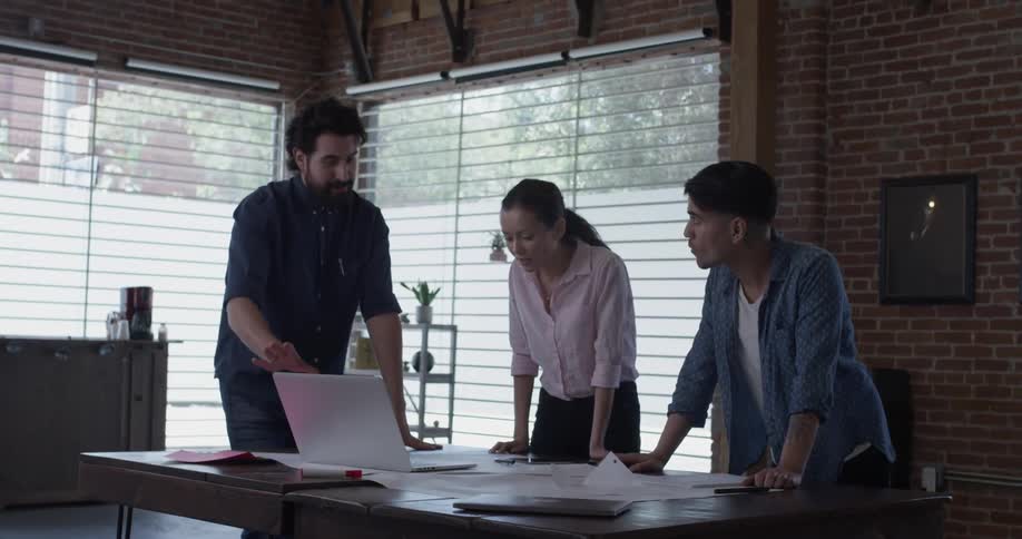A man carries a laptop to the table to show the group